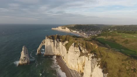 Flying-over-the-natural-arch-of-Etretat-with-the-city-and-bay-in-background.